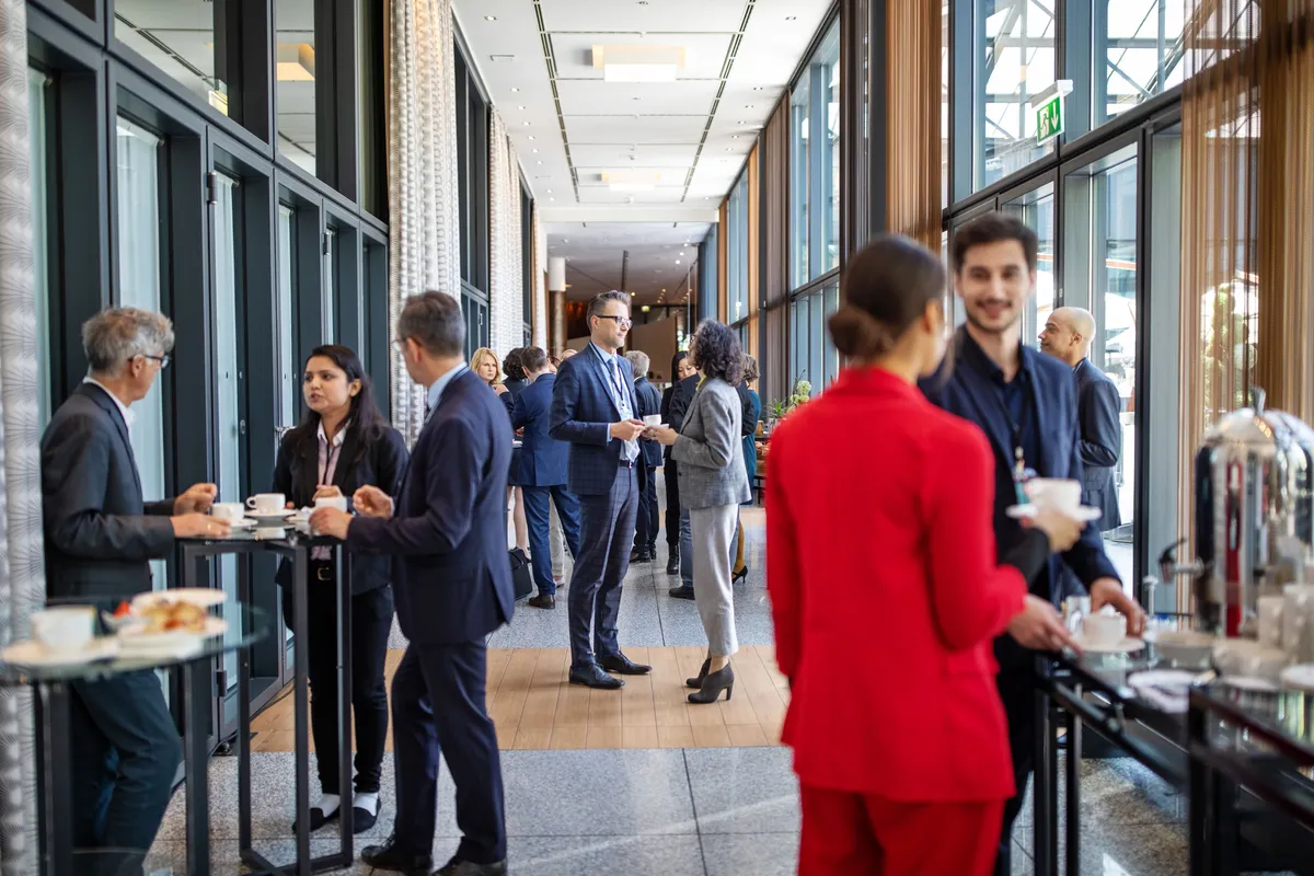 Professionals talking over coffee in a conference corridor